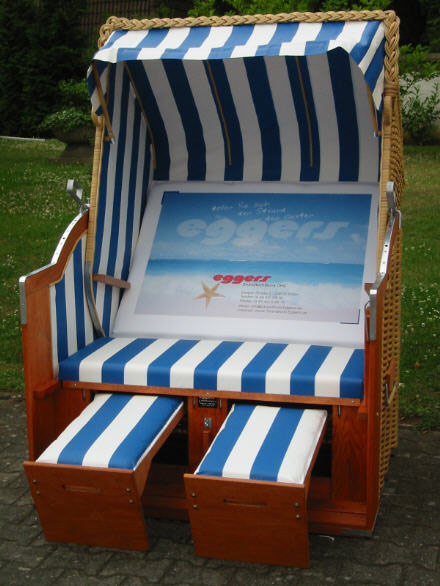 logouUFhC0WqxhI6K Der 2-Sitzer Strandkorb hat ein Geflecht aus PVC beige mit gestreifter Folie in blau-weiß. Das Rückenpolster ist mit Werbung unserer Firma bedruckt.