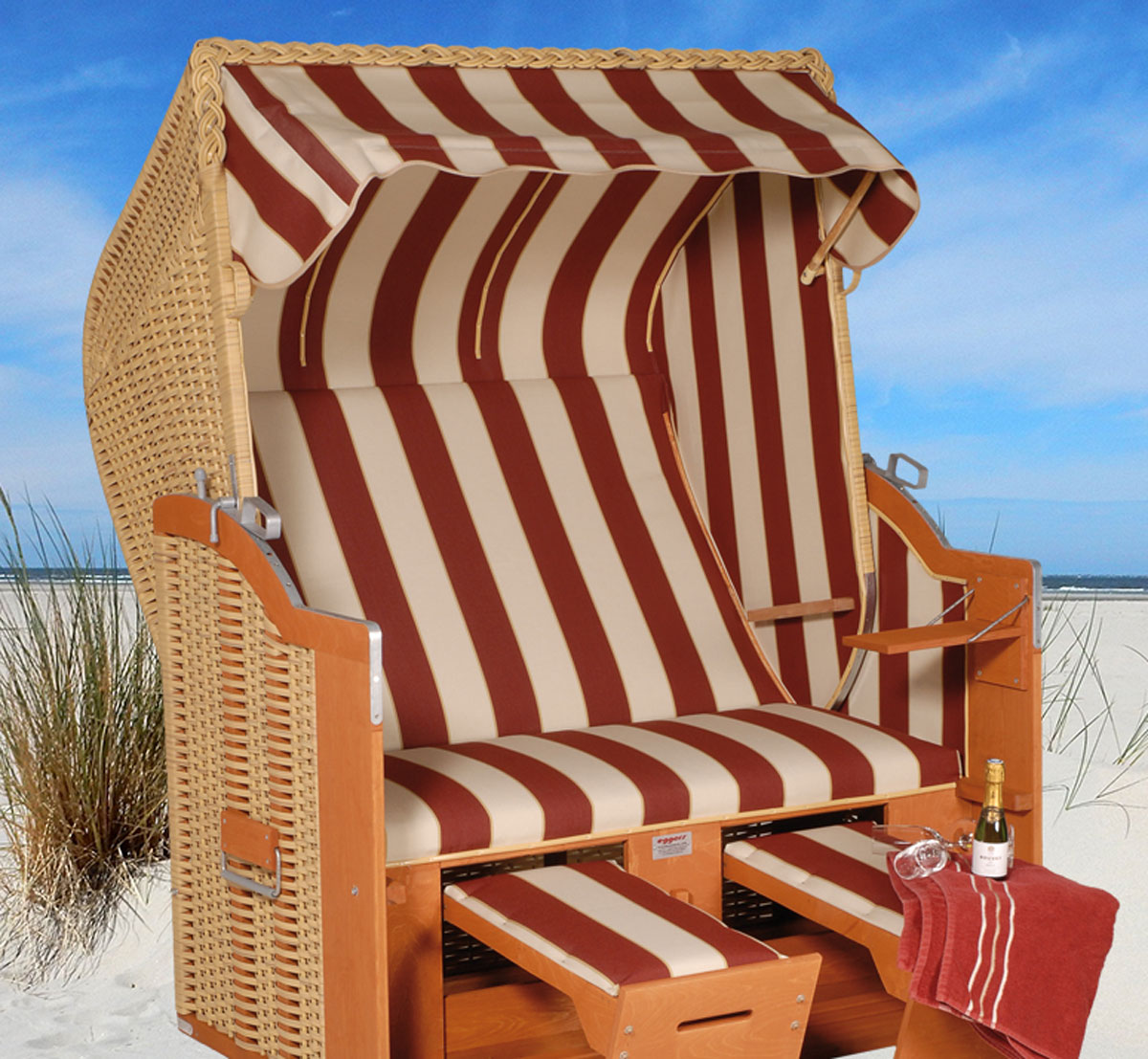Der 2-Sitzer Strandkorb hat ein Geflecht aus PE in der Farbe beige mit einem gestreiften Stoffdesign in braun-beige.