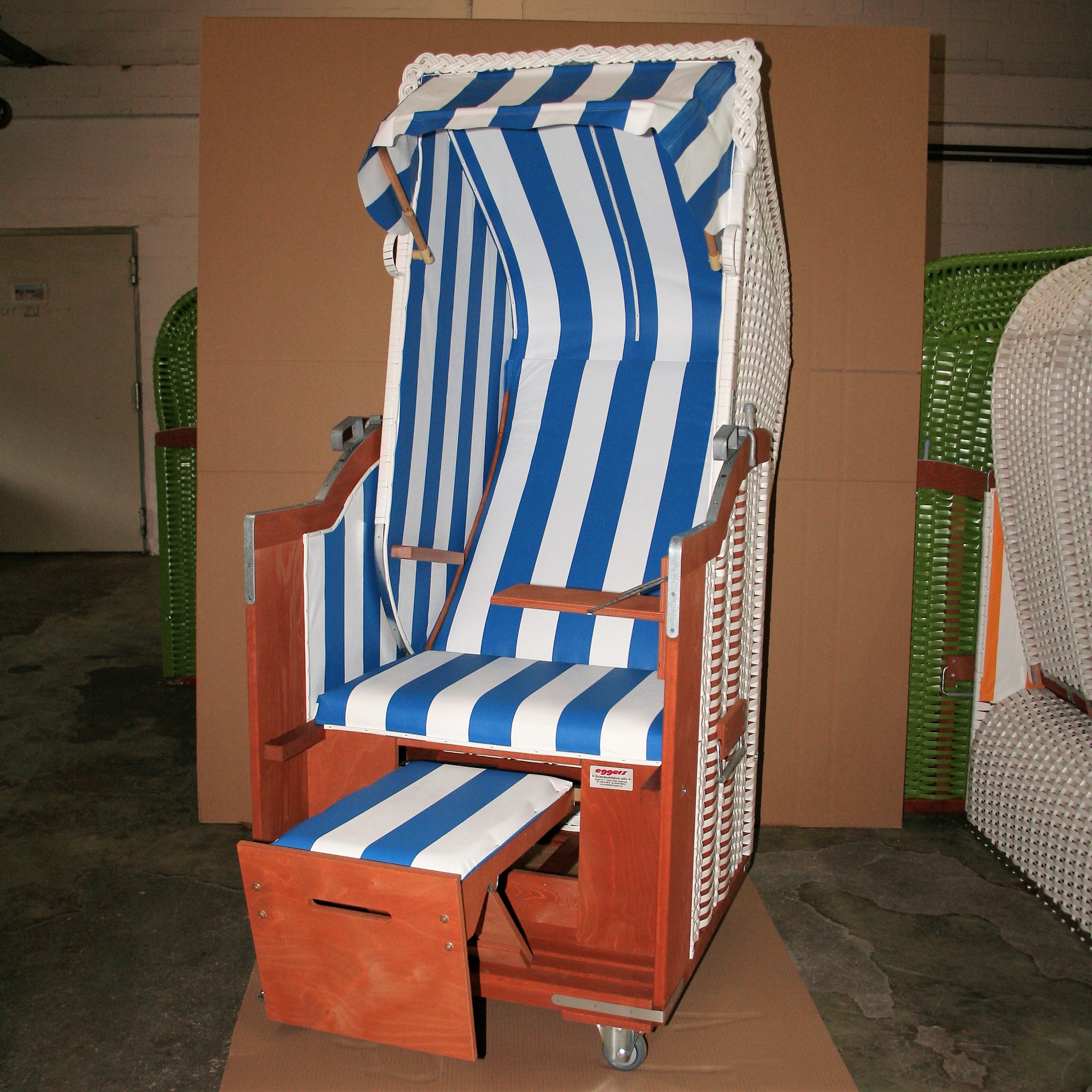 Der 1-Sitzer Strandkorb hat ein Geflecht aus PVC in der Farbe weiß mit gestreifter Plastikfolie in blau-weiß.