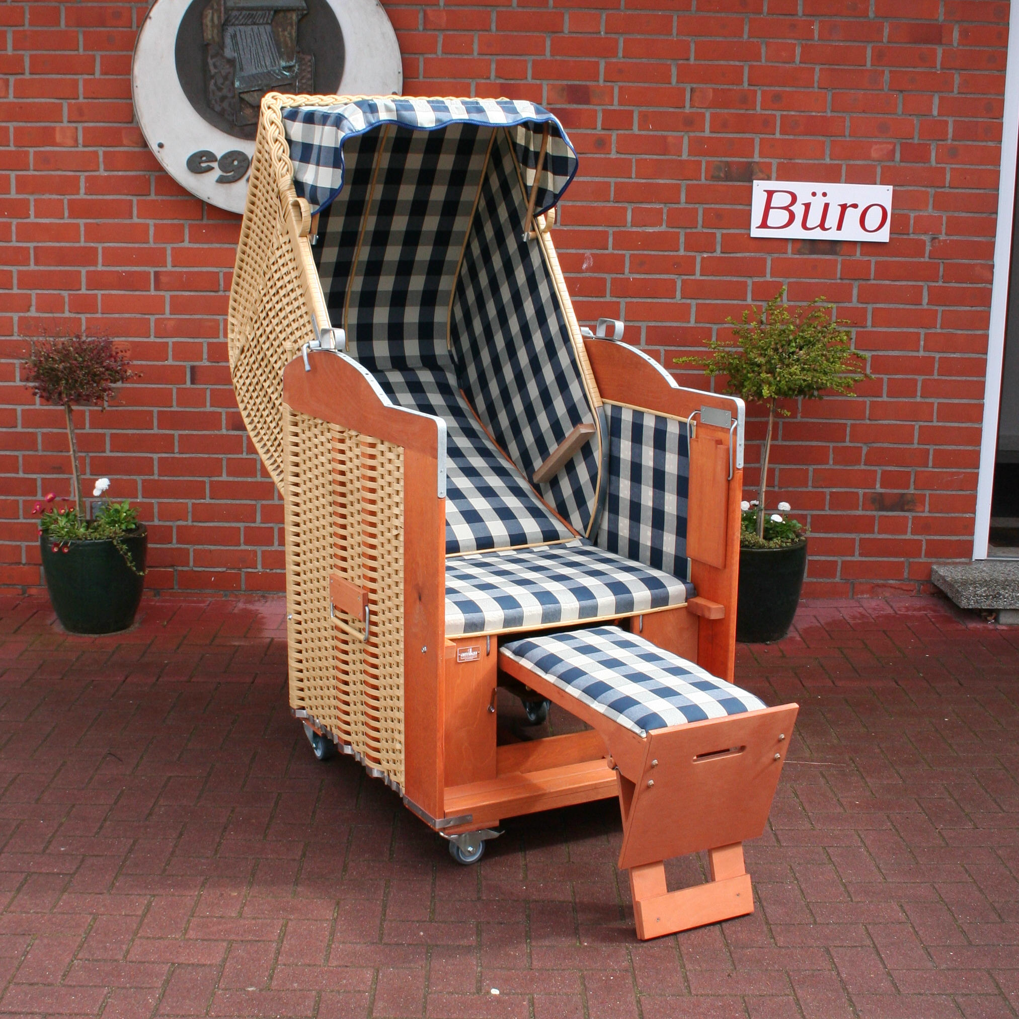Der 1-Sitzer Strandkorb hat ein Geflecht aus PVC in der Farbe beige mit einem karierten Stoffdesign in blau-beige.