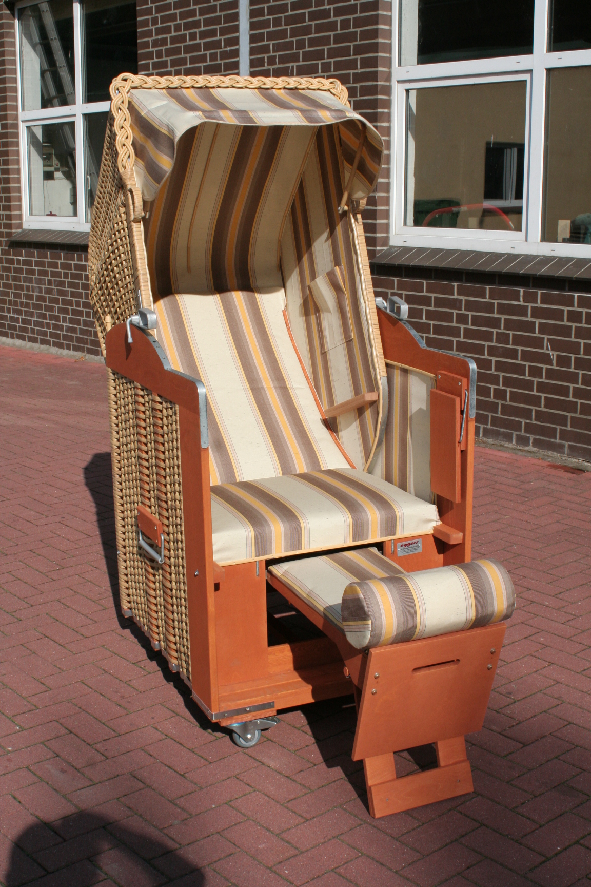 Der 1-Sitzer Strandkorb hat ein Geflecht aus PE in der Farbe beige  mit einem gestreiften Stoffdesign in braun-beige-gelb.